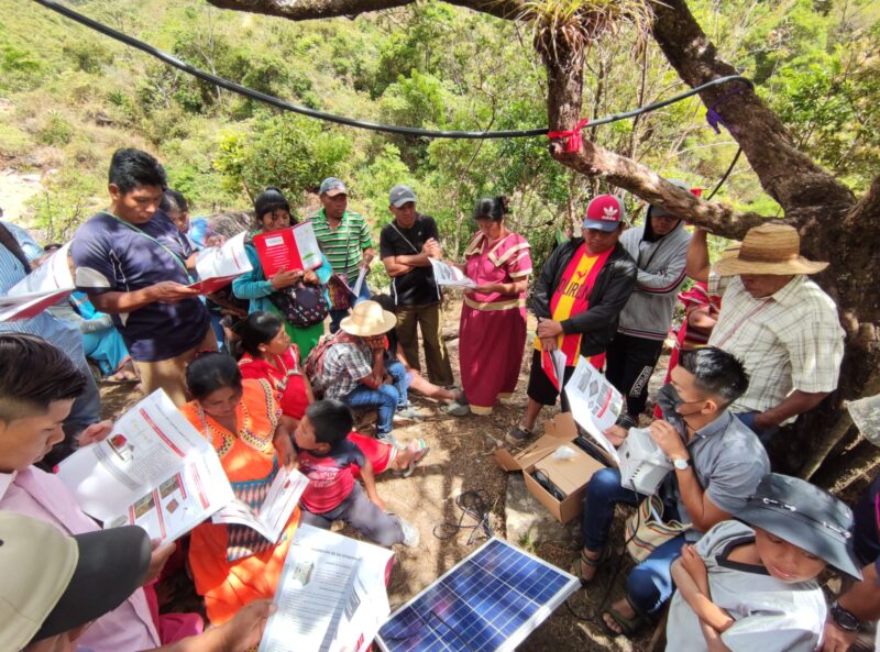 A group of Indigenous people from the Community of Guayabal de Peña Blanca, Comarca Ngäbe Buglé are learning how to use a portable Photovoltaic System under a big tree.